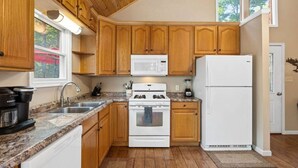 Eine Küche mit Holzschränken, einem weißen Herd, einer Mikrowelle und einem Kühlschrank.