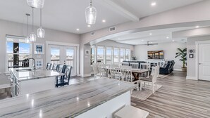 A spacious kitchen with a marble island, white cabinetry, and pendant lighting.
