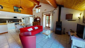 Una sala de estar acogedora con un sofá rojo, techo de madera y una chimenea.