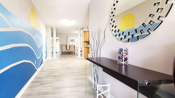 A hallway with a blue mural, a glass partition, and a decorative mirror.