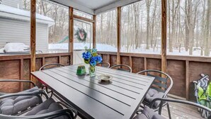 A covered patio with a table and chairs, a wreath on the window, and a snowy landscape outside. - Private Home in Poconos -Country Club-New Renovated heated Pool, Beach, & more  (Tobyhanna)