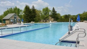 A swimming pool with clear blue water, surrounded by lounge chairs and umbrellas, and a small building in the background. - Private Home in Poconos -Country Club-New Renovated heated Pool, Beach, & more  (Tobyhanna)