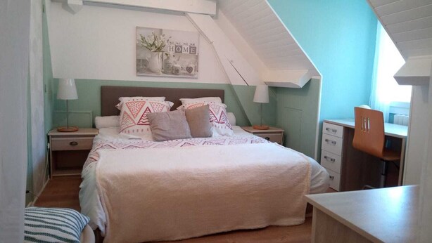 Un dormitorio con cama, mesitas de noche, escritorio y silla.