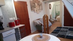 Un espacio habitable compacto con kitchenette, una zona de comedor con dos tazas de café, un sofá y una silla.