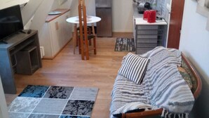 Un espacio habitable compacto con un altillo para el dormitorio, una kitchenette y una zona de comedor.