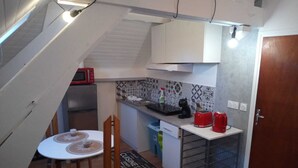 Una cocina compacta con comedor, microondas, tostadora y cafetera.
