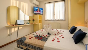 A hotel room with a bed, a TV, a desk with a laptop, a mirror, and a window with curtains. - DesenzanoLoft Dolce Vita (Desenzano del Garda)