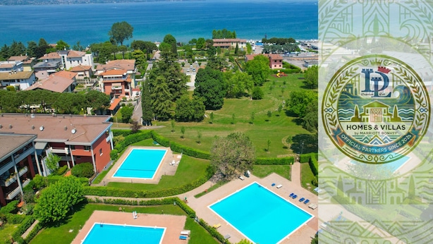 An aerial view of a residential area with two swimming pools, a large body of water, and a mountainous backdrop. - DesenzanoLoft Dolce Vita (Desenzano del Garda)