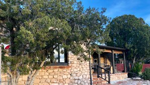 A stone building with a wooden porch, surrounded by trees and a stone pathway. - 1930's Stone Cottage with spectacular views! (Lake Montezuma)