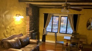A cozy living room with a leather sofa, a drum, a wooden chair, and a dining table. - 1930's Stone Cottage with spectacular views! (Lake Montezuma)