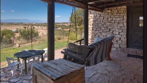 A covered outdoor seating area with stone walls and a view of a desert landscape. - 1930's Stone Cottage with spectacular views! (Lake Montezuma)