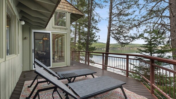 A deck with two lounge chairs and a glass door leading to an interior space.