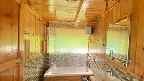 Un baño de madera con una bañera, un lavabo y un espejo.