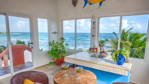 Una habitación con vistas al océano, una pequeña cocina y un área de descanso con una mesa y sillas.