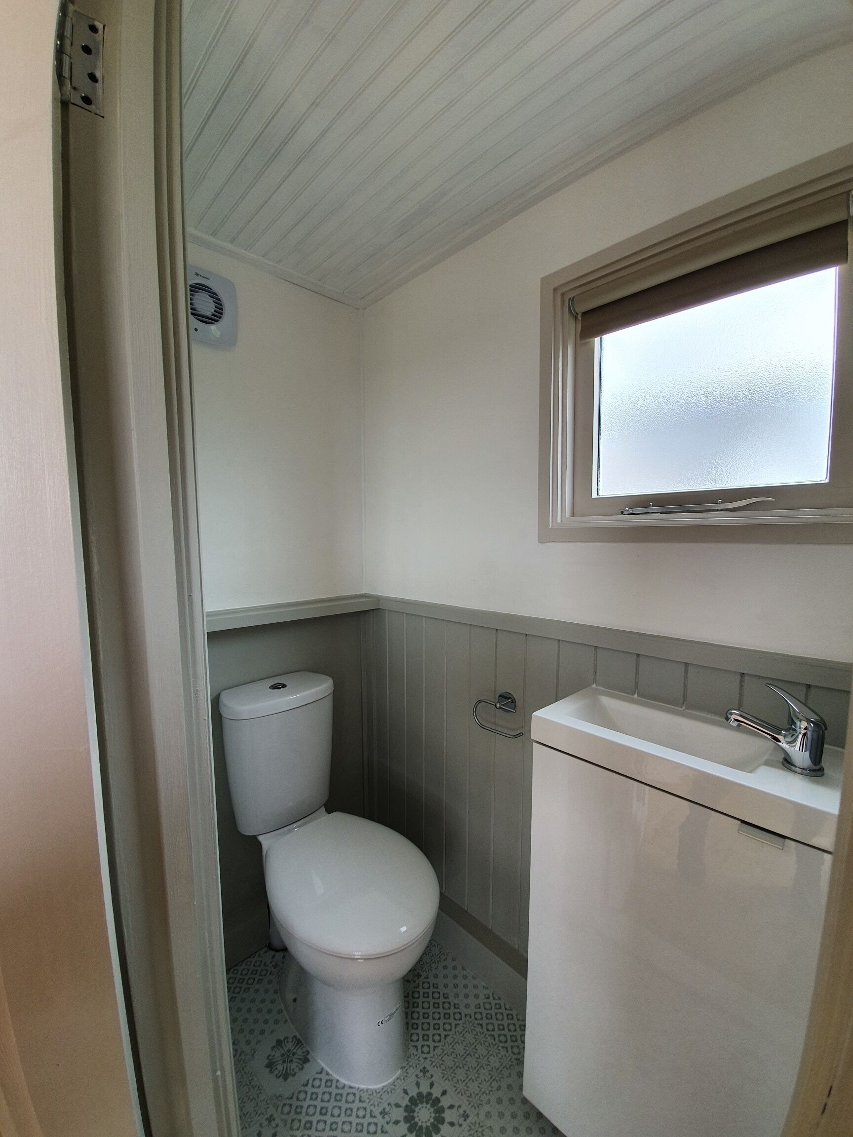 Een kleine badkamer met toilet, wastafel en raam.