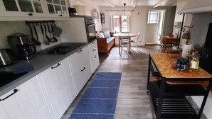A compact kitchen with white cabinets, a wooden dining table, and a blue mat. - Swedish idyll - dreamlike secluded location - close to the lake - sauna - pool table (Nybro)