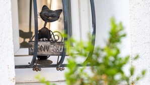 Une décoration en métal représentant un chat, posée sur un rebord de fenêtre, avec une pancarte sur laquelle on peut lire « BIENVENUE ».