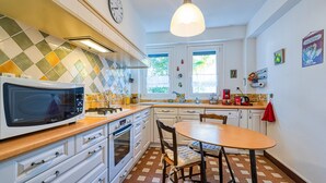 Une cuisine avec des meubles blancs, un four à micro-ondes, une cuisinière et une table à manger avec des chaises.