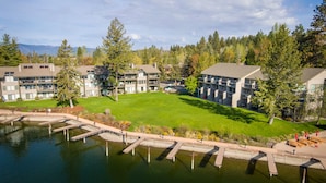 A residential building with multiple balconies, a well-maintained lawn, and a dock extending into a body of water. - Stunning views of the lake, private balcony & gorgeous fireplace - Spacious Marina Cay Getaway (Bigfork)