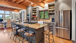 A spacious kitchen with a large island, stainless steel appliances, and wooden ceiling beams. - High Haven | Breathtaking Mountain Views! (Black Mountain)