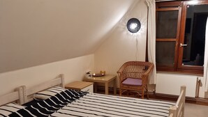 Ein Schlafzimmer mit einem großen Bett, einem kleinen Tisch, einem Stuhl und einem Fenster mit Vorhängen.