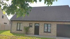 Ein zweistöckiges Haus mit Ziegeldach, einer Haustür und einer Garagentür.