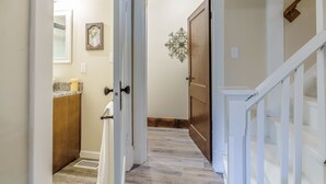 A hallway with a wooden door, a white railing, and a marble countertop with a candle. - Remodeled Rocheport Sunflower House - A Bungalow in Historic Rocheport (Rocheport)