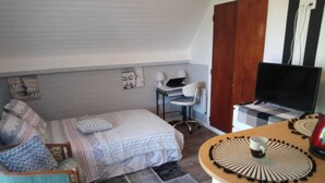 Een kleine, knusse slaapkamer met een bed, een bureau, een stoel en een televisie.