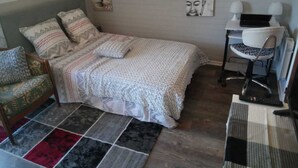 Een slaapkamer met een bed, bureau, stoel en vloerkleed.