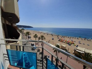 A balcony with a view of a beach, palm trees, and a clear sky. - Hostal Lloret Playa (Lloret de Mar)