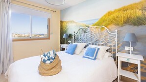 A bedroom with a large bed, a view of the city, and a mural of grass and sand. - Home2Book Bright Penthouse Médano, Terrace & Pool (El Medano)