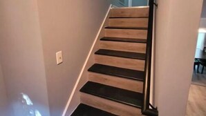 A staircase with wooden steps and black handrails, leading to a room with a door at the top. - Quaint home w/ Private Pool Near Lake Murray – Ideal for Families and Friends (Columbia)