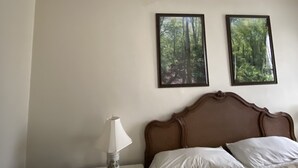 A bedroom with a bed, a nightstand, a lamp, and two framed pictures on the wall. - Lodging Near Public Transportation (Acton)