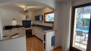 Eine kompakte Küche mit eingebautem Backofen, Mikrowelle und Kaffeemaschine. Ein kleines Fenster bietet Blick ins Freie.