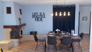 Ein Essbereich mit Tisch für vier Personen, Kamin und einer Wand mit einem motivierenden Zitat.
