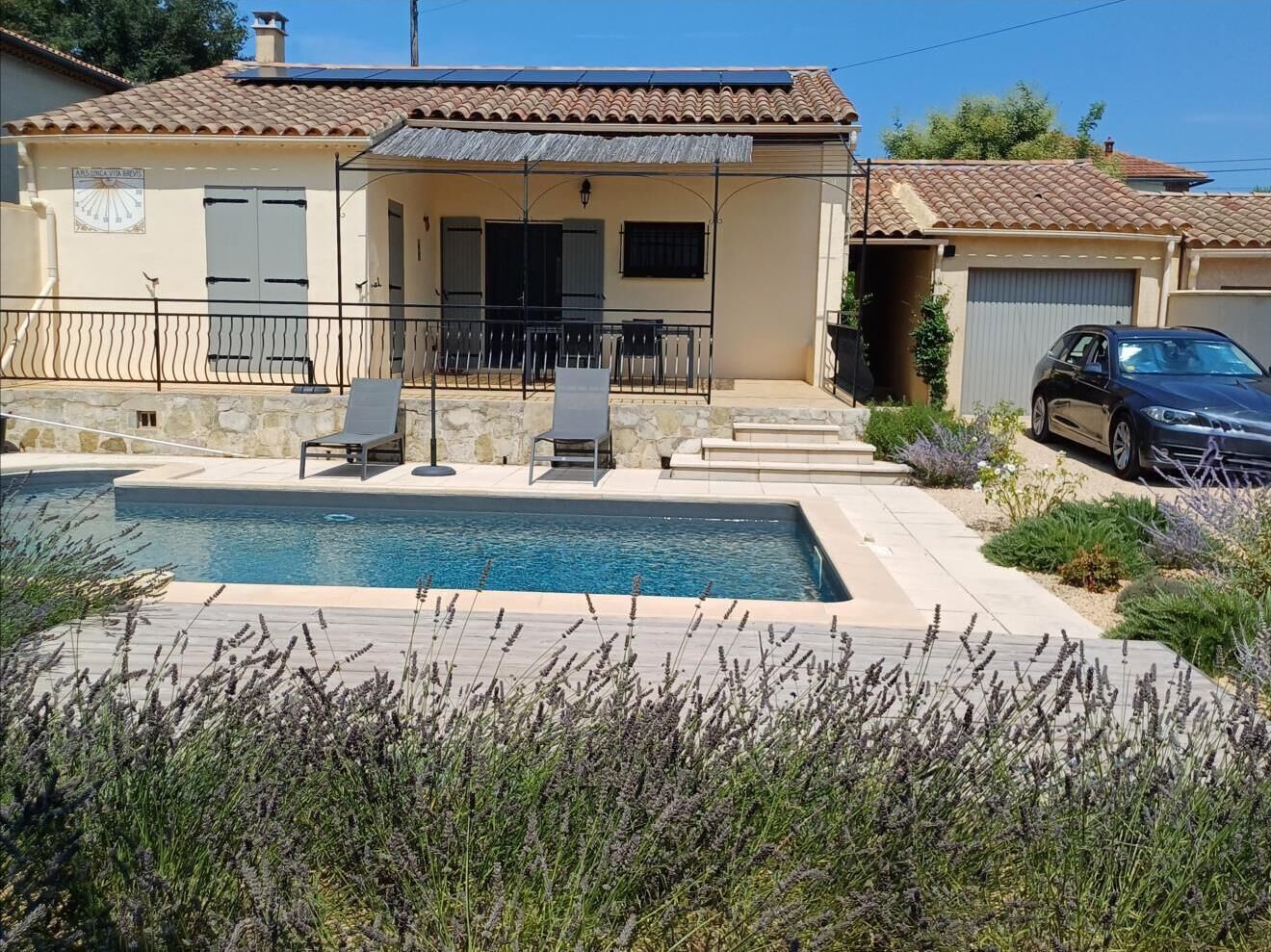 Una casa con piscina, area salotto esterna e un'auto nelle vicinanze.