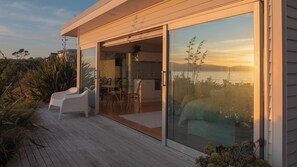 Una casa moderna con terraza, puertas corredizas y vista al agua.