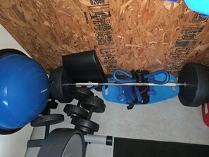 A gym with exercise equipment, including a blue exercise ball, a barbell, and weight plates. - PRIVATE SUITE⭐️OUTERBANKS⭐️CENTRAL ⭐️KDH⭐️WALK TO SOUND SUNSET OR BEACH⭐️ (Kill Devil Hills)