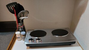 Een keuken met een ingebouwde kookplaat, een klein aanrecht en een prullenbak.