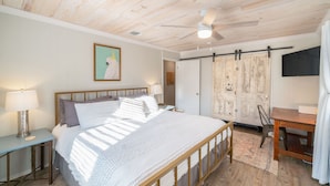 A bedroom with a wooden ceiling, a bed with white bedding, a desk, and a chair. - Trendy Pet-friendly House w/ Patio near Lake LBJ (Kingsland)