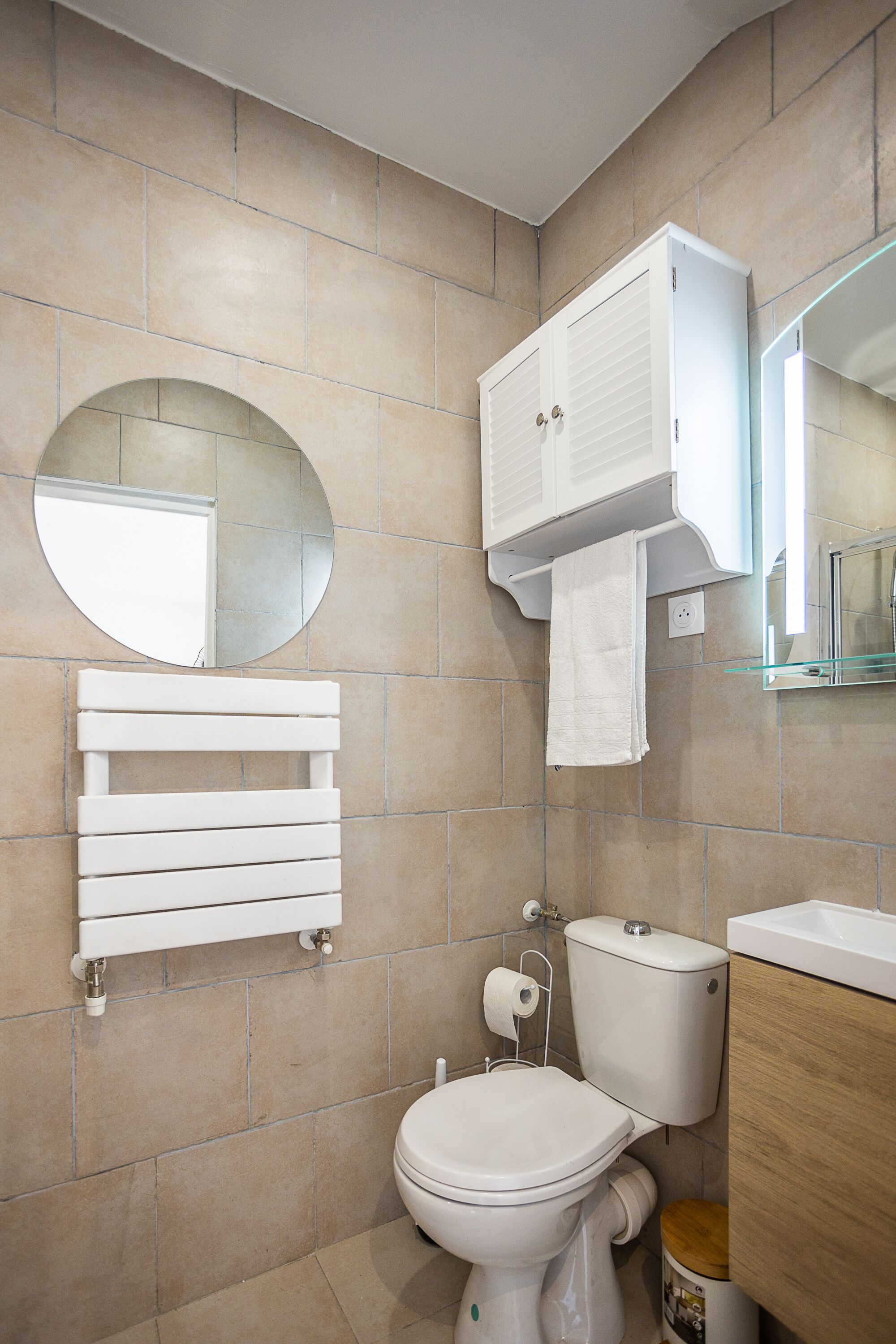 A bathroom with a toilet, a sink, a mirror, and a towel rack.