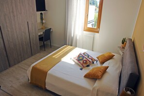 A neatly arranged bedroom with a bed, bedside table, and a desk with a chair. - B&B Erilla (Lonato del Garda)