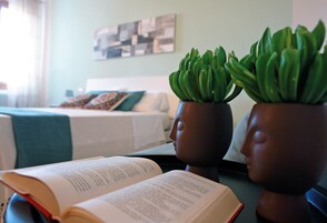 Una stanza con un letto, un libro e due piante in vasi su un tavolo.