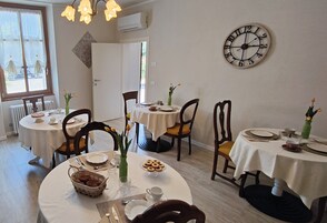 Zona pranzo con tavoli rotondi, sedie e un orologio a muro.