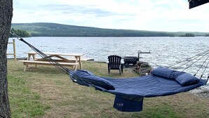 A hammock suspended from a tree, a picnic table, and a chair by a lakeside. - Railway camp on Moosehead Lake (greenville)