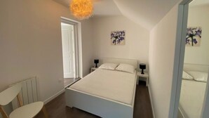 A bedroom with a bed, two bedside tables, a chair, and a ceiling light fixture. - Villa POPEE for 8 people (Cucq)