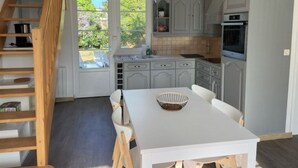 A kitchen with a white table, grey cabinets, and a wooden staircase. - Villa POPEE for 8 people (Cucq)
