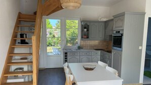A kitchen with a white table and chairs, a wooden staircase, and grey cabinets. - Villa POPEE for 8 people (Cucq)