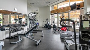 A modern gym with various exercise equipment, large windows, and a view of the outside. - Okanagan four seasons paradise with shared pool and hot tub (Westbank)
