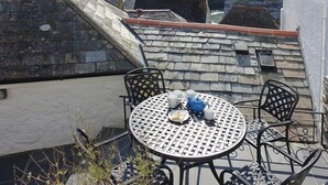Ett runt bord med stolar på en takterrass, med utsikt över en by med traditionella hus och en kyrka.